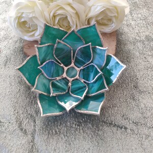 May include: A green stained glass succulent with silver accents. The glass is textured and has a white swirl pattern.