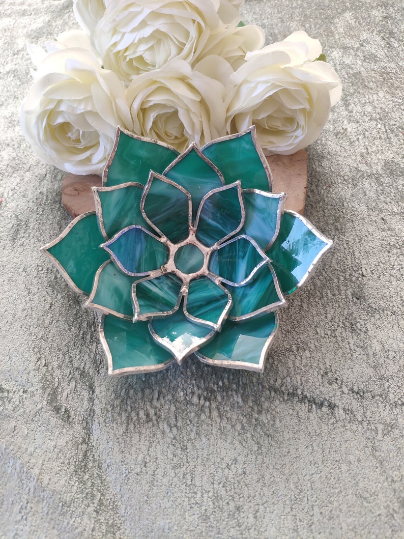 May include: A green stained glass succulent with silver accents. The glass is textured and has a white swirl pattern.