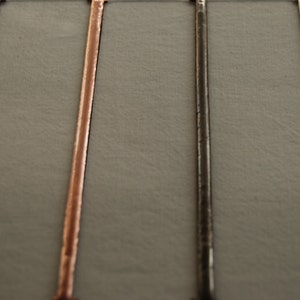 May include: Four metal rods in different finishes: silver, black, copper, and gold. The rods are arranged vertically against a gray background.