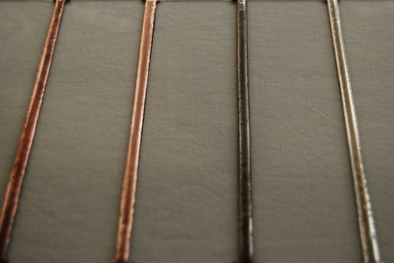 May include: Four metal rods in different finishes: silver, black, copper, and gold. The rods are arranged vertically against a gray background.