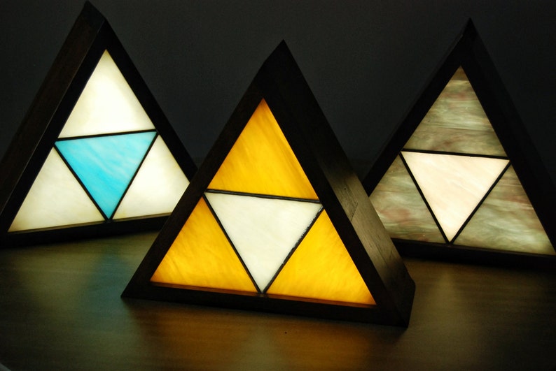 K&ouml;nnte beinhalten: Drei dreieckige Lampen mit Buntglasfenstern in den Farben Blau, Gelb und Grau. Die Lampen sind aus Holz und haben eine dunkelbraune Oberfl&auml;che.