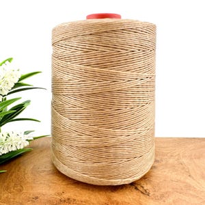 May include: A spool of natural brown paper cord, wound tightly and ready for crafting projects.