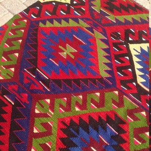 May include: A colorful rug with a geometric pattern in shades of red, blue, green, and black. The rug has a traditional design with intricate details.
