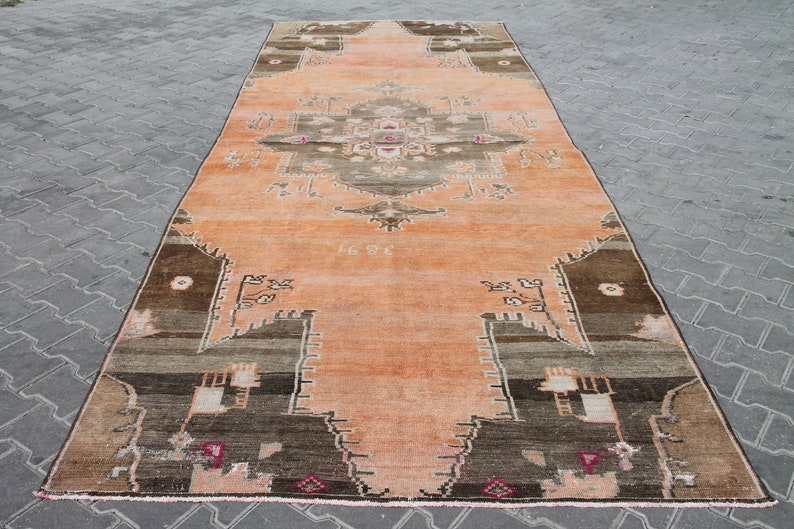 May include: A rectangular, vintage-style rug with a central medallion design. The rug features a warm color palette of peach, brown, and gray tones. The rug's dimensions are not visible in the image.