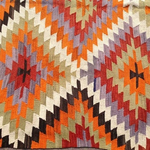 May include: A colorful rug with a geometric pattern in shades of orange, red, purple, brown, and white.
