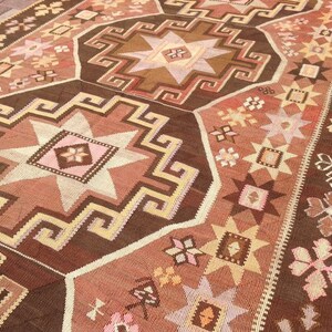 Puede incluir: Una alfombra turca tradicional con un patr&oacute;n geom&eacute;trico marr&oacute;n, beige y rosa. La alfombra presenta un dise&ntilde;o de estrella central rodeado de estrellas m&aacute;s peque&ntilde;as y motivos florales.