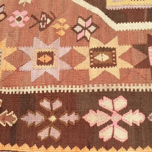 Puede incluir: Primer plano de una alfombra de color marr&oacute;n y rosa con intrincados dise&ntilde;os geom&eacute;tricos. La alfombra presenta una variedad de motivos florales y formas de estrellas.