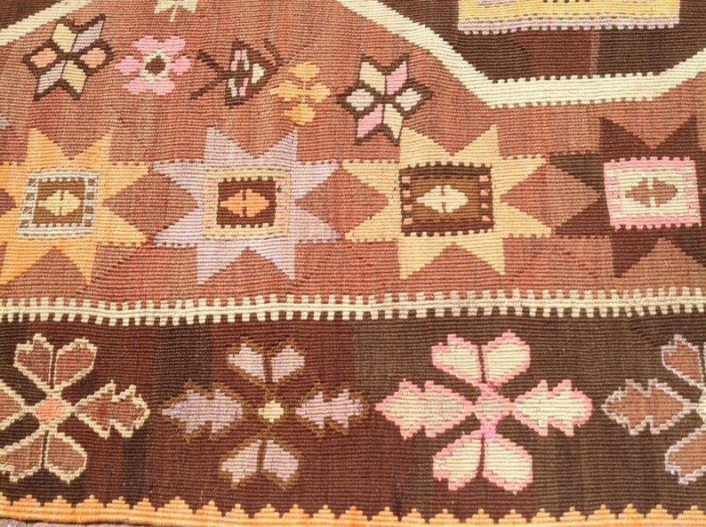 Puede incluir: Primer plano de una alfombra de color marr&oacute;n y rosa con intrincados dise&ntilde;os geom&eacute;tricos. La alfombra presenta una variedad de motivos florales y formas de estrellas.