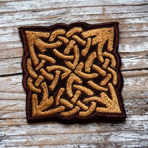 Könnte beinhalten: Ein brauner und goldener gestickter Patch mit einem keltischen Knotendesign.