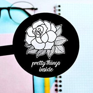 May include: Black and white sticker with a rose illustration and the text "pretty things inside".