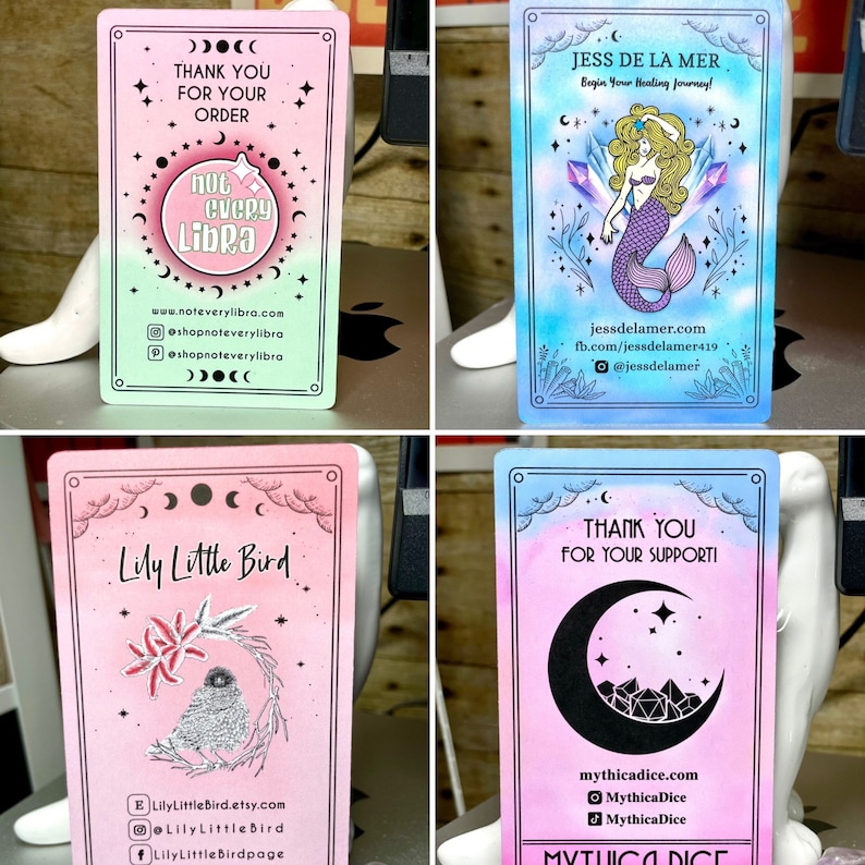 May include: Four different business cards with a watercolour background and illustrations. The first card is green and pink with a moon and stars and the text "not every libra". The second card is blue and pink with a mermaid and the text "Jess de la Mer". The third card is pink with a bird and the text "Lily Little Bird". The fourth card is pink and blue with a crescent moon and the text "Mythica Dice".