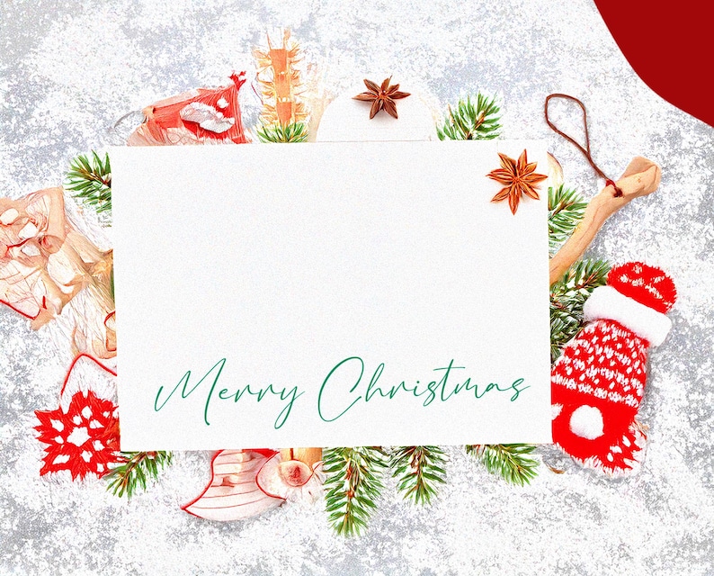Puede incluir: Una tarjeta blanca con el texto "Merry Christmas" escrito en cursiva verde. La tarjeta est&aacute; rodeada de una variedad de decoraciones navide&ntilde;as, incluyendo ramas de pino, adornos rojos y blancos y una estrella de madera.
