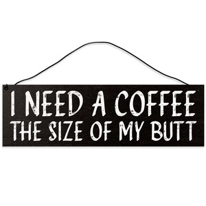 May include: A rectangular black wooden sign with white distressed text that reads "I NEED A COFFEE THE SIZE OF MY BUTT". The sign has a thin black wire for hanging.
