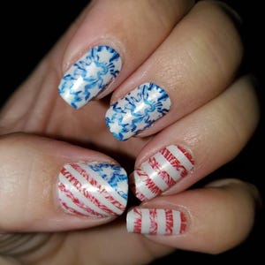 May include: Close-up of fingernails with red, white and blue nail art designs. The designs include stripes and floral patterns.