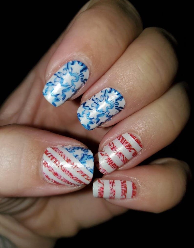 May include: Close-up of fingernails with red, white and blue nail art designs. The designs include stripes and floral patterns.