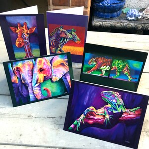 May include: Five greeting cards with colorful animal illustrations. The cards feature a giraffe, zebra, elephants, tiger, and a lizard. The cards are all different sizes and shapes.