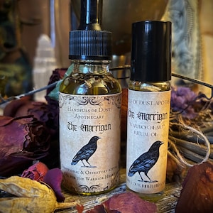May include: Two small bottles of oil with black labels and droppers. The labels have a black crow illustration and the text "Handfuls of Dust Apothecary The Morrigan Warrior Heart Ritual Oil".