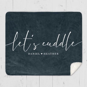 Puede incluir: Una manta de forro polar azul oscuro con el texto "let's cuddle" en escritura cursiva blanca. Debajo del texto, dice "DANIEL &hearts; HEATHER".