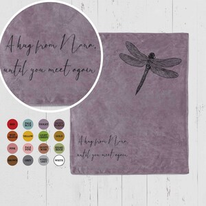 Peut inclure: Une couverture en molleton douce et violette avec un motif de libellule et le texte "A hug from Nana. until you meet again".