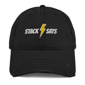 Puede incluir: Gorra de béisbol negra desgastada con el texto "STACK SATS" bordado en blanco y un rayo amarillo. La gorra tiene una visera precurvada y un aspecto vintage.