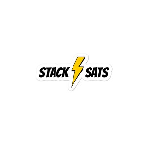 Pu&ograve; includere: Un adesivo bianco con la scritta "STACK SATS" in nero, con un fulmine giallo al centro. L'adesivo ha un bordo nero.