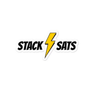Pu&ograve; includere: Un adesivo bianco con la scritta "STACK SATS" in nero, separata da un fulmine giallo. L'adesivo ha un bordo bianco ed &egrave; su sfondo bianco.