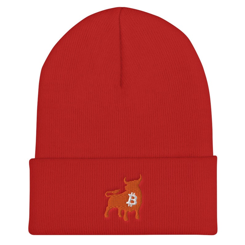 May include: A red beanie with a folded brim. The beanie features an embroidered design of a bull with a Bitcoin symbol in the center. The bull is orange, and the Bitcoin symbol is silver.