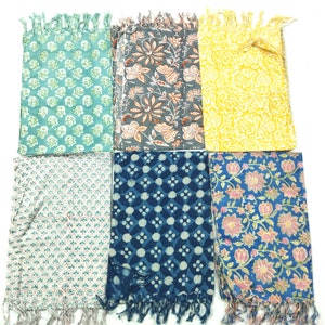 May include: Six cotton scarves with different floral and geometric patterns. The scarves are in shades of blue, green, yellow, and pink. Each scarf has a fringe on the ends.