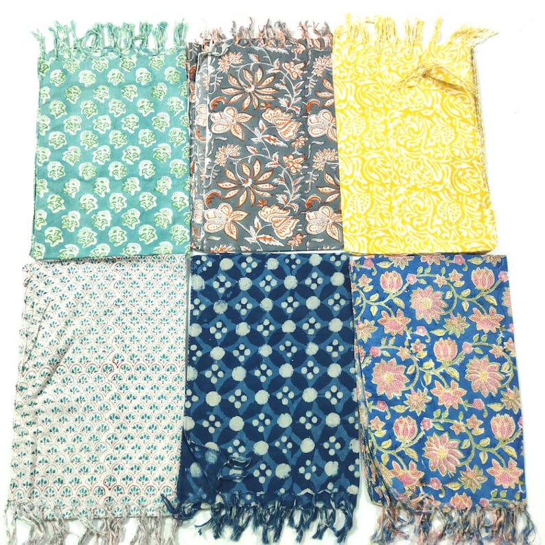May include: Six cotton scarves with different floral and geometric patterns. The scarves are in shades of blue, green, yellow, and pink. Each scarf has a fringe on the ends.