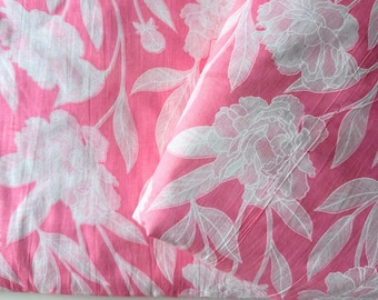 May include: Pink fabric with a white floral pattern. The fabric features a repeating design of large white peonies and leaves.