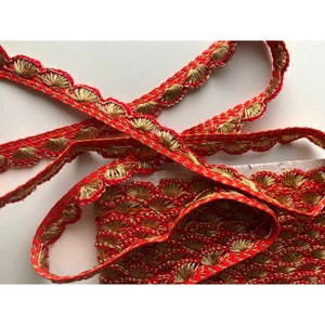 May include: Red and gold trim with a scalloped edge. The trim has a repeating pattern of small, gold, fan-shaped designs.
