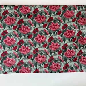 May include: A green fabric with a repeating pattern of pink flowers and green leaves.