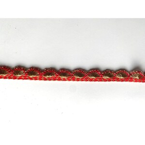 May include: Red and gold trim with a scalloped edge. The trim is made of a woven fabric with a textured surface.