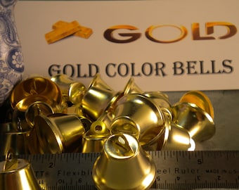 Puede incluir: Una colección de campanas brillantes de color dorado. Las campanas están agrupadas, con una regla en primer plano. Un letrero en el fondo dice "GOLD COLOR BELLS."