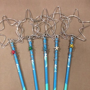 May include: Five blue wands with a mermaid design and a star-shaped wire bubble wand attached to the top. The stars are decorated with different coloured beads.