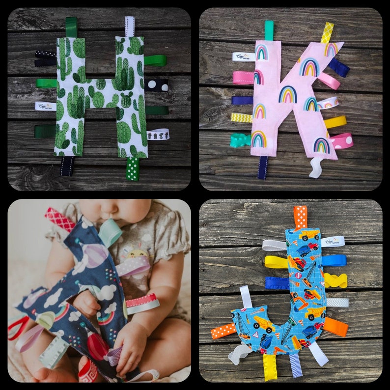 May include: Four fabric alphabet letter toys with colorful ribbons attached. The letters are H, K, J, and a blue letter with a hot air balloon design.