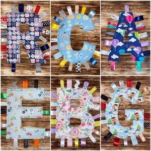 May include: A set of six baby sensory blankets, each featuring a different letter of the alphabet. The blankets are made of soft fabric and have a variety of textures and colors. Each blanket has a different pattern, including baseballs, flowers, and farm animals. The blankets are perfect for babies to explore and learn.