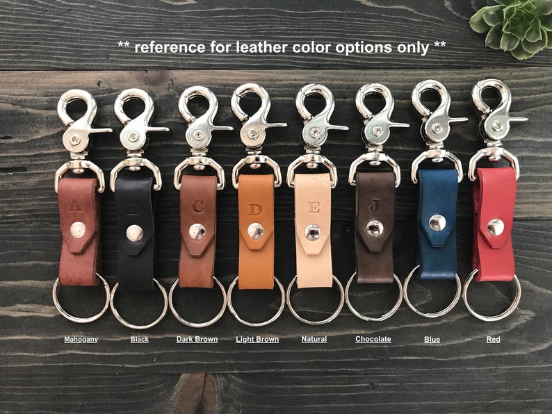 May include: Nine leather keychains with silver swivel clips and rings. The keychains are in the colors mahogany, black, dark brown, light brown, natural, chocolate, blue, and red.