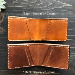 May include: Two leather wallets, one light brown with cream stitching and one dark brown with cream stitching.  *Light Brown w/ Cream and *Dark Brown w/ Cream are written below each wallet.