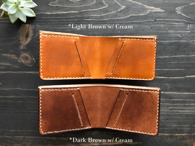 May include: Two leather wallets, one light brown with cream stitching and one dark brown with cream stitching.  *Light Brown w/ Cream and *Dark Brown w/ Cream are written below each wallet.