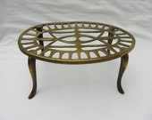 Antique solid brass oval trivet. Pierced top, paw legs. Kitchen pot holder, teapot stand, plant pot stand. Fireside accessory