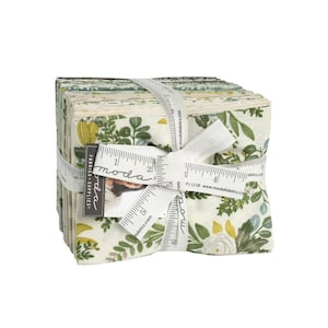 May include: A stack of 12 fat quarters of fabric featuring a floral print with white, green, and yellow flowers on a cream background. The fabric is tied with a white ribbon and a Moda Fabrics label.