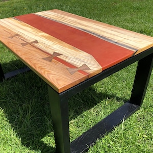 May include: A wooden coffee table with a red epoxy resin inlay and black metal legs. The table top has a natural wood grain pattern and features decorative wooden accents.