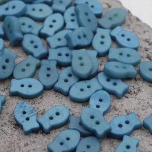 Può includere: Una collezione di bottoni a forma di pesce blu chiaro. Ogni bottone ha due fori per cucire. I bottoni sono realizzati in un materiale solido e hanno una superficie leggermente strutturata. Ideali per progetti di cucito e artigianato.