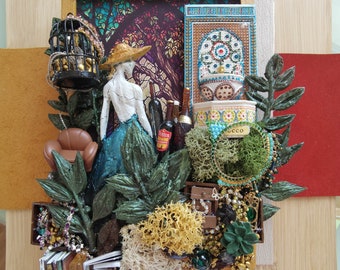 May include: A mixed media art piece featuring a woman figurine, a birdcage, a small fountain, and various decorative elements. The piece is set against a backdrop of a stained glass window and a leafy green background.