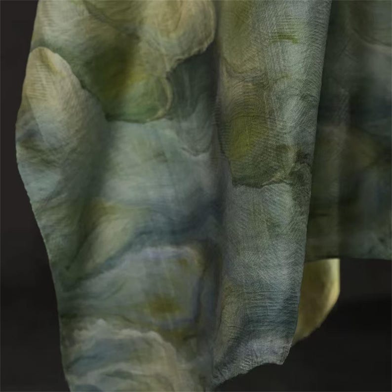 May include: A draped fabric with a watercolor-like pattern in shades of green, blue, and cream. The fabric has a textured appearance, with visible woven threads. The overall effect is soft and flowing, suggesting a scarf or shawl.