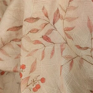 Op de afbeelding: Close-up van een beige stof met een subtiel rasterpatroon. Sierlijke takken met roodbruine bladeren en kleine oranje bessen zijn kunstzinnig op het oppervlak gedrukt, wat een natuurlijk, botanisch ontwerp cre&euml;ert.