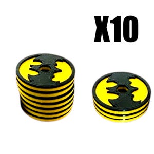 May include: Two yellow and black Batman logo-shaped objects. One is a stack of seven, the other is a single object. The text "X10" is above the objects. The objects have a black outline and a yellow center.