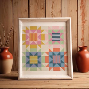 May include: A framed art print featuring a colorful geometric design. The artwork showcases four star-like patterns in pastel shades of pink, yellow, blue, and green, set against a cream background. The frame is white, and the piece is displayed on a wooden surface.