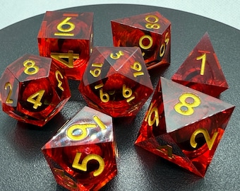 May include: A set of seven polyhedral dice in various shapes. The dice are transparent red with gold numbers. These dice are for tabletop role-playing games like Dungeons and Dragons.